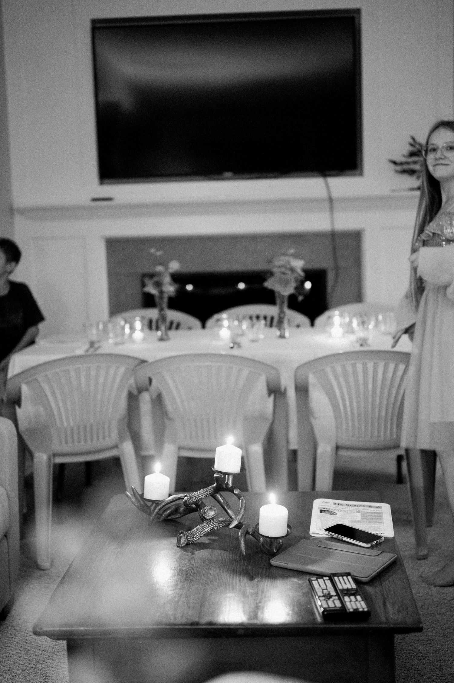 Black and white photo series showing a dimly lit table with candles and white chairs in a minimalist interior setting.