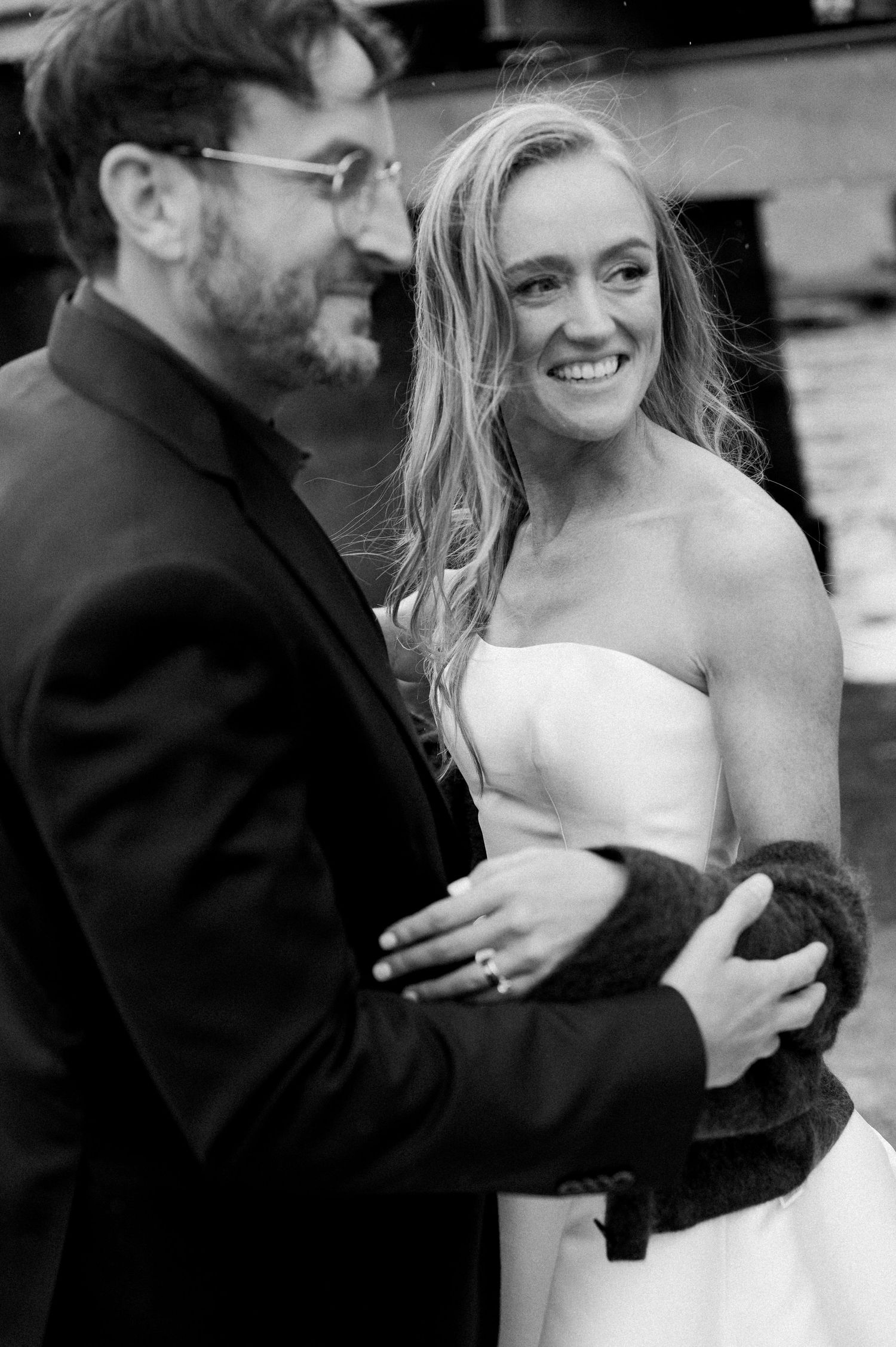 A couple in black and white sharing a tender moment while dancing at what appears to be their wedding celebration.