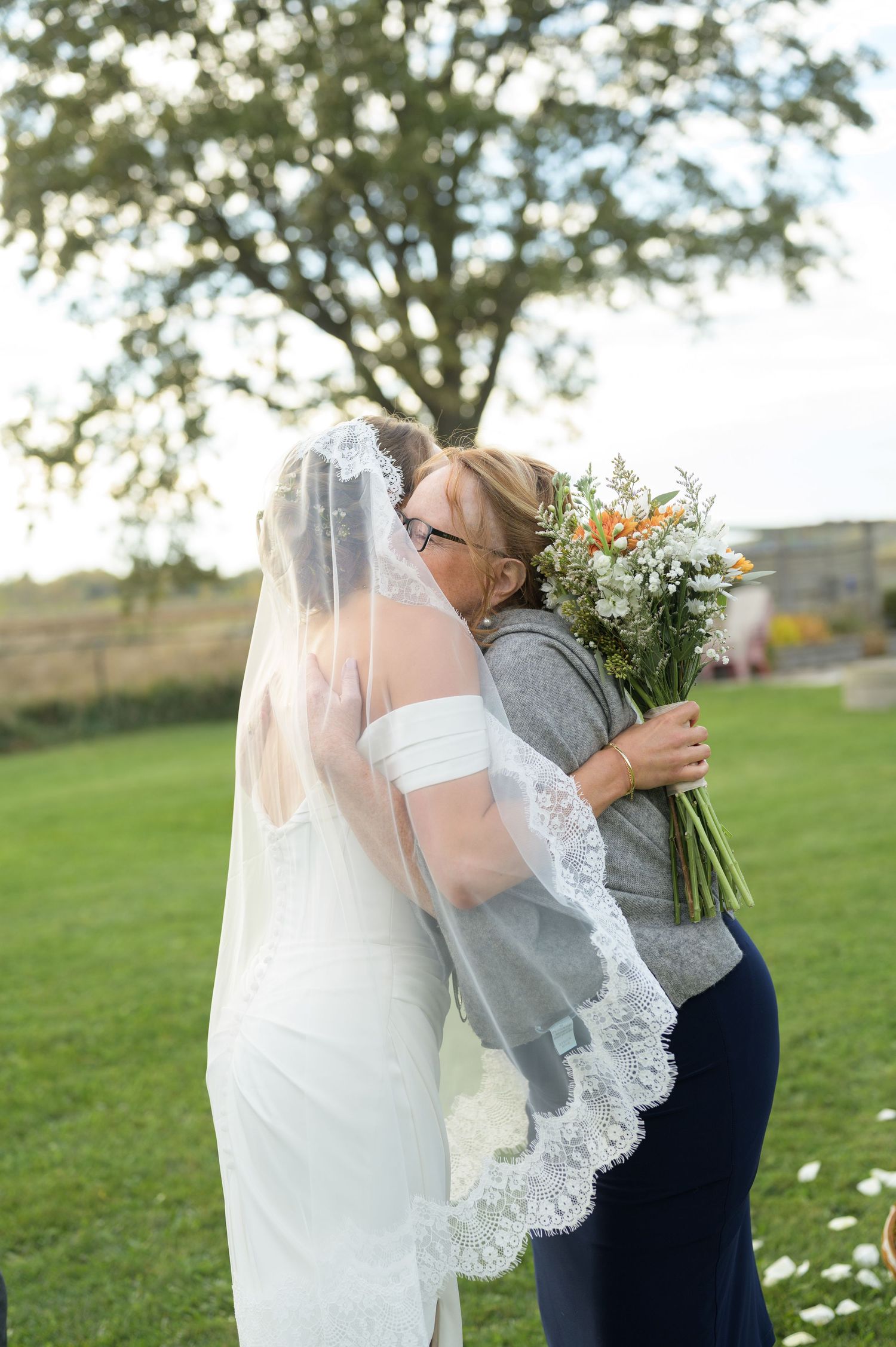 A tender moment captured between a couple with a white lace veil in an outdoor setting.