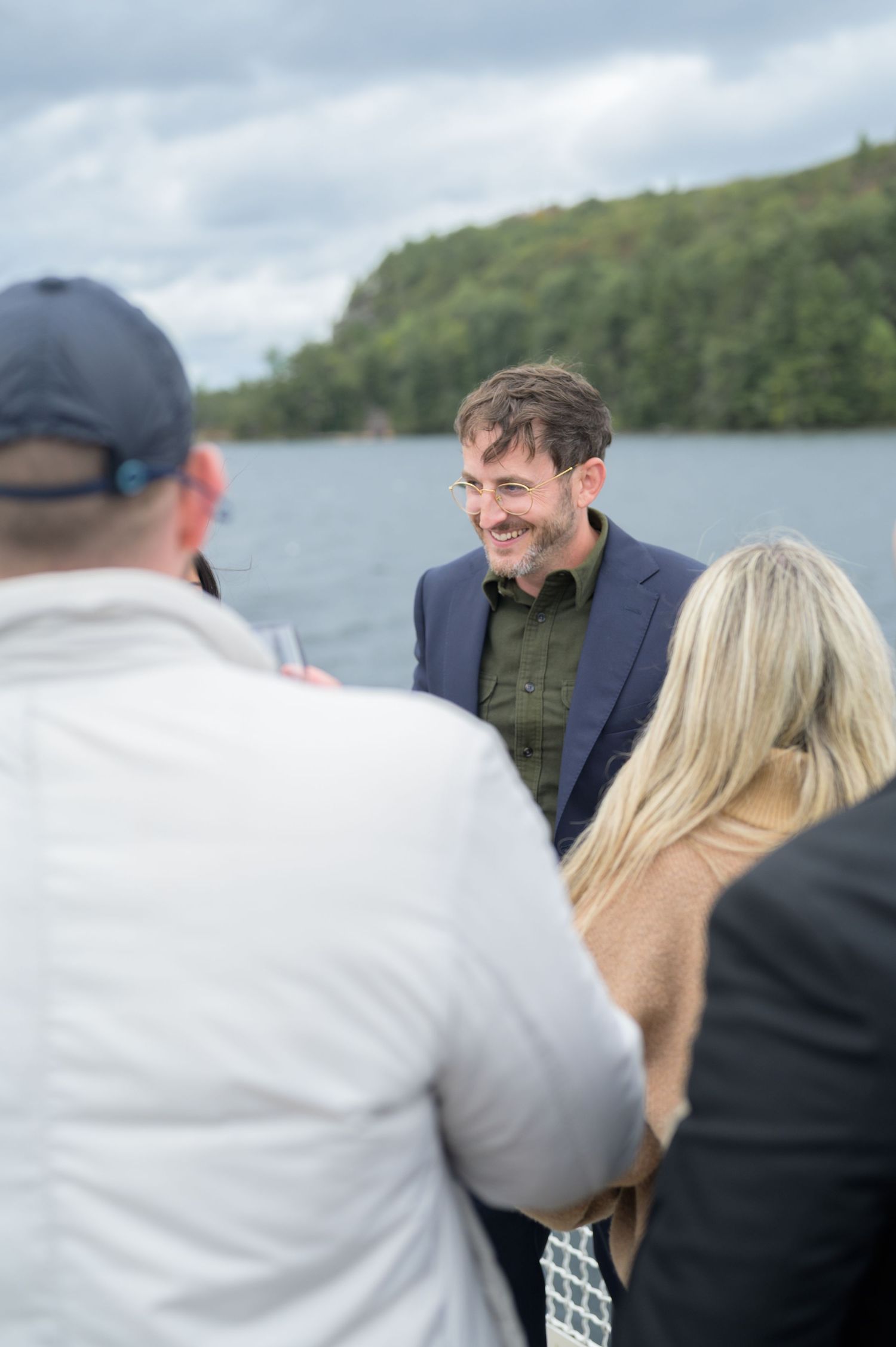 People enjoying conversation and laughter while boating on a lake with green hills in the background.