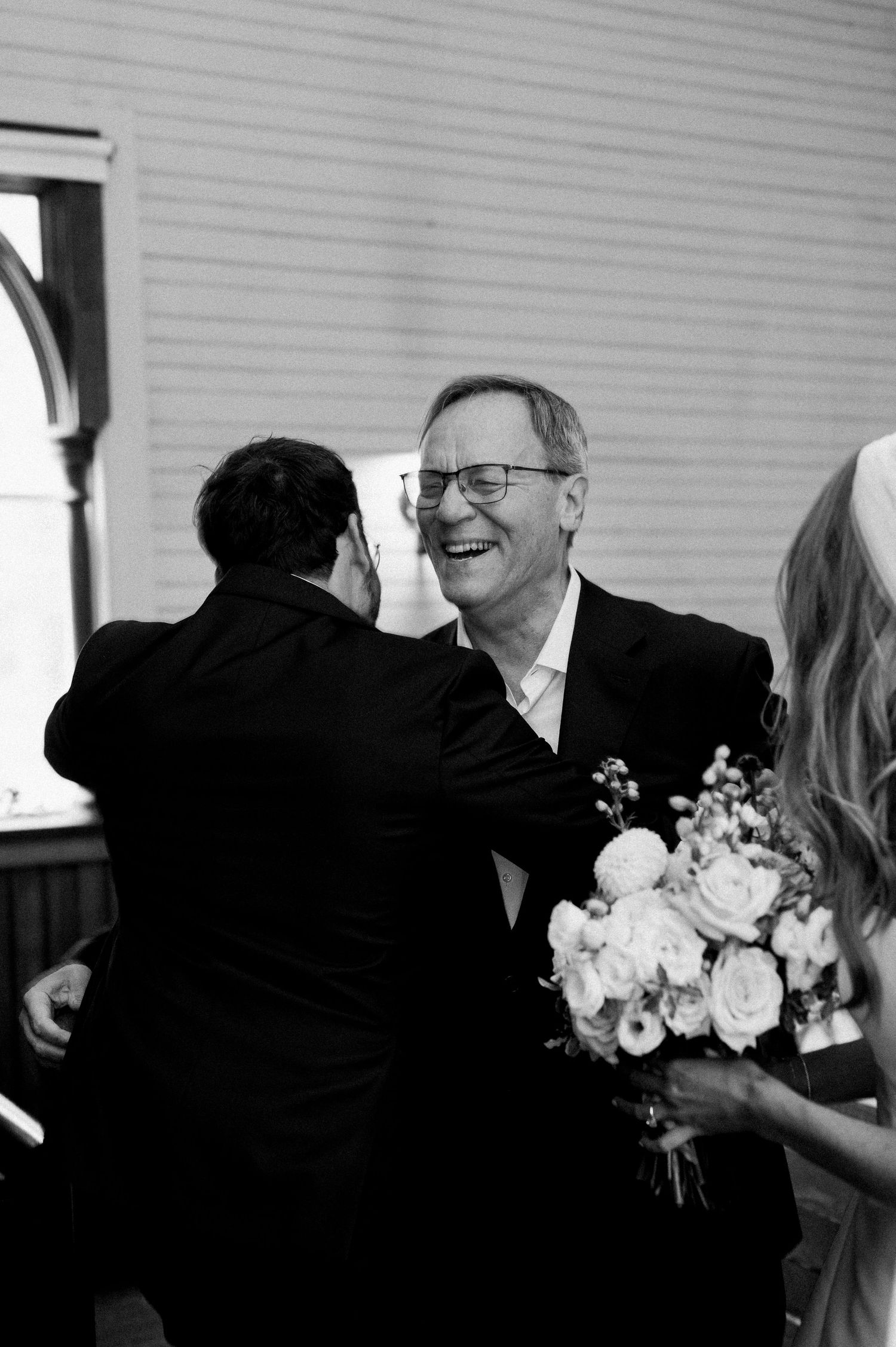 A series of black and white wedding photos showing joyful candid moments with flowers and smiles.