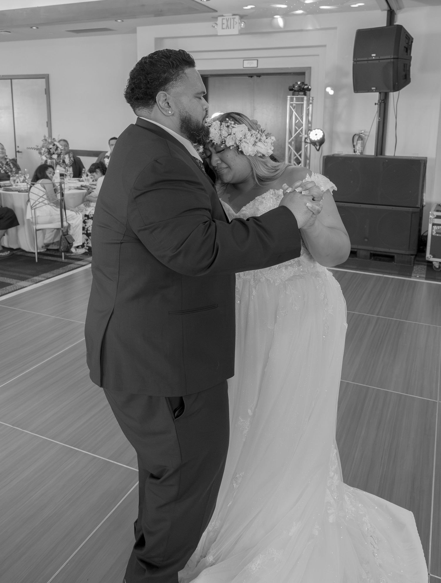Black and white photo of a bride and groom sharing their first dance at a wedding reception.