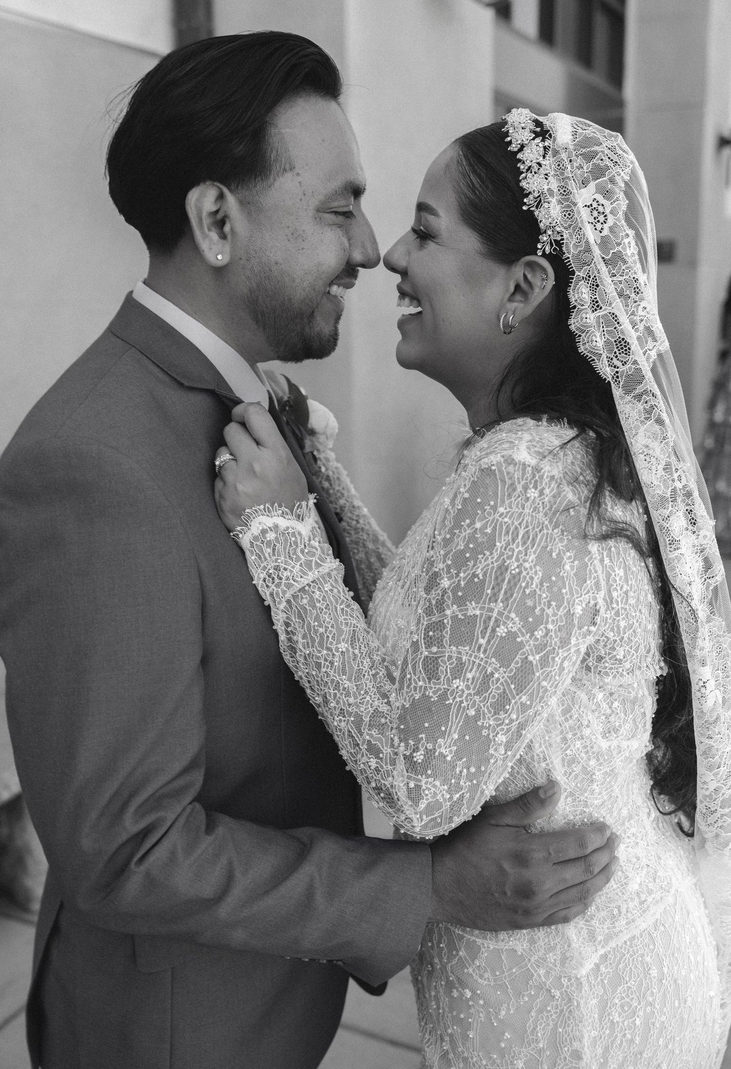 Black and white photo of a smiling bride and groom embracing on their wedding day, sharing a joyful moment.