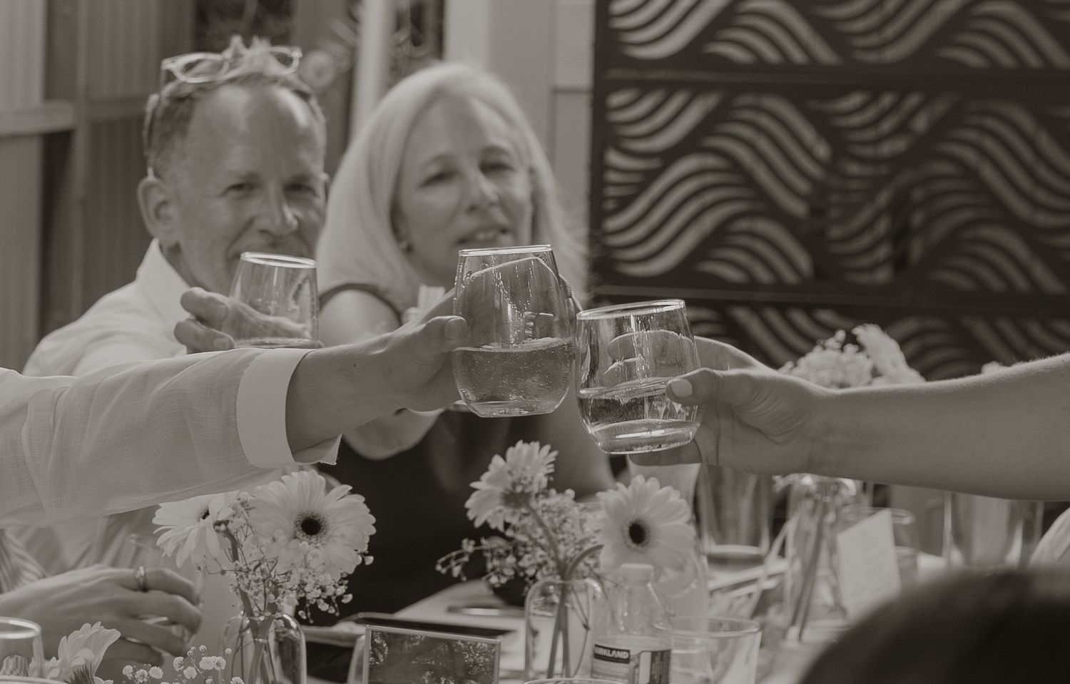 Black and white photo of guests clinking glasses in a toast at a formal dinner party celebration.