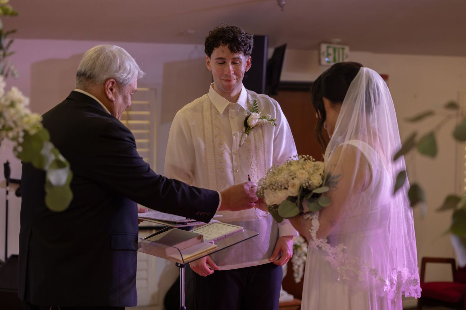 Bride and groom exchanging vows with officiant during intimate church wedding ceremony.