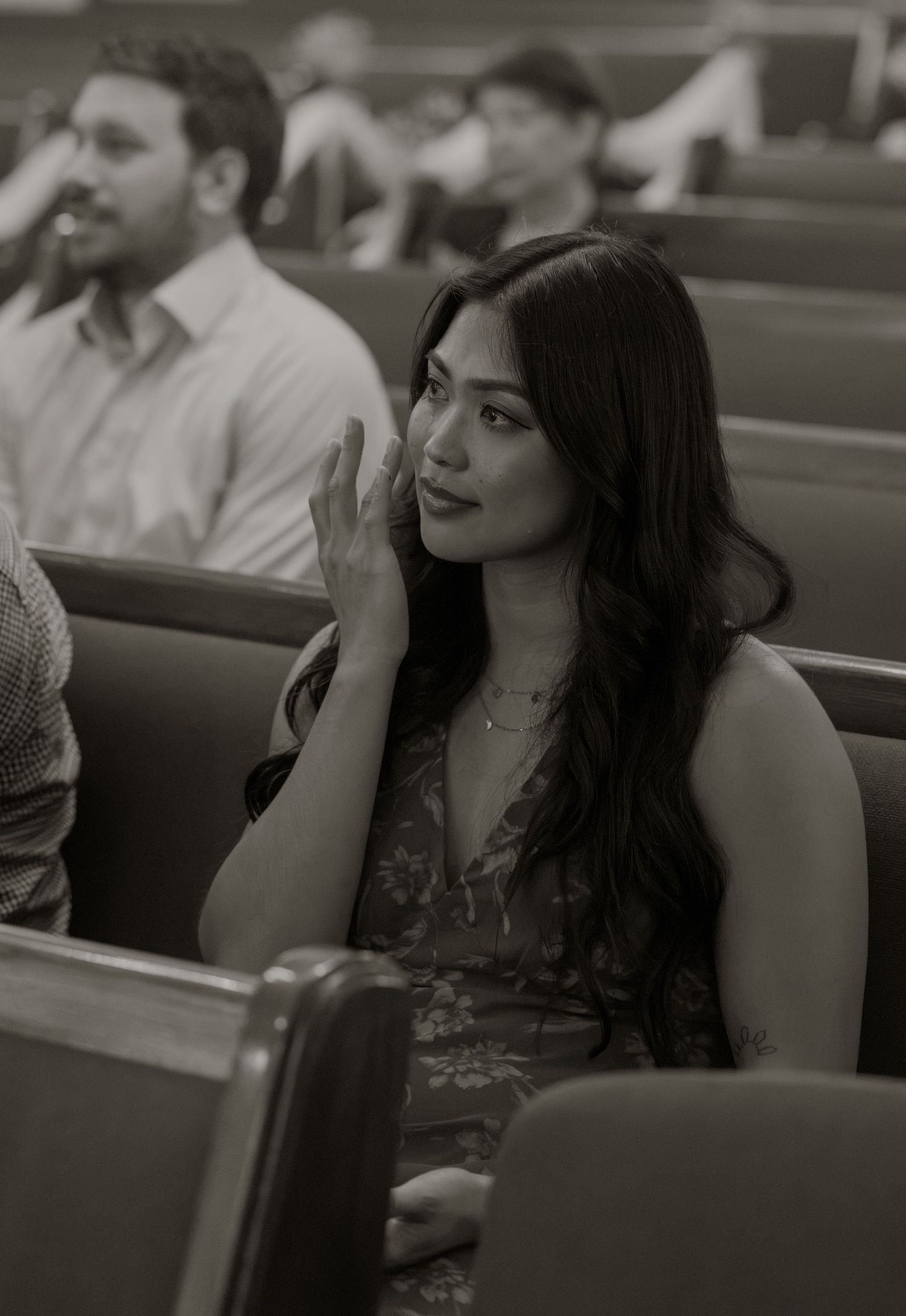 Woman wiping tears in church pew during wedding ceremony in black and white photo.