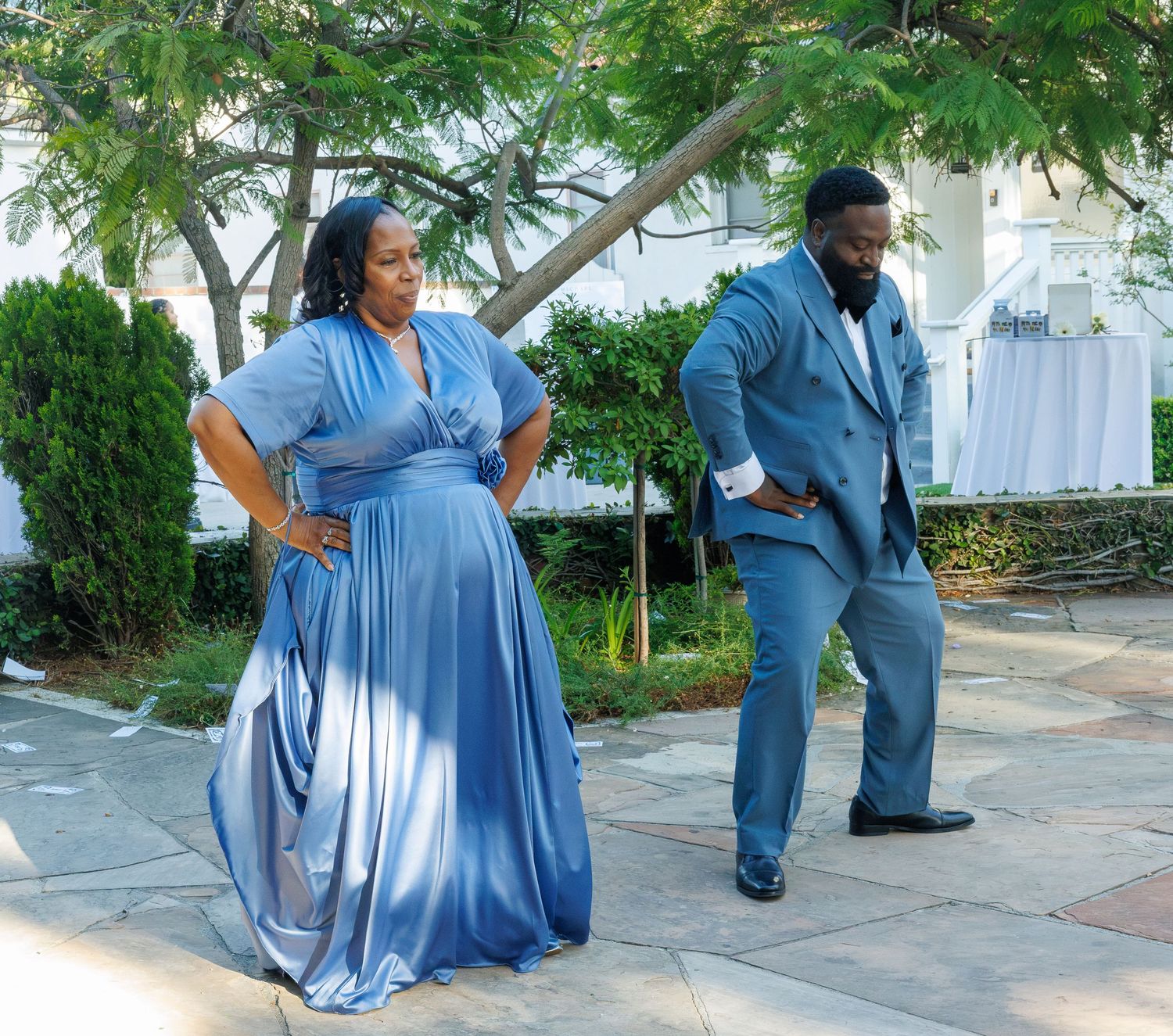 Couple posing playfully outdoors in coordinating blue formal attire at a wedding.