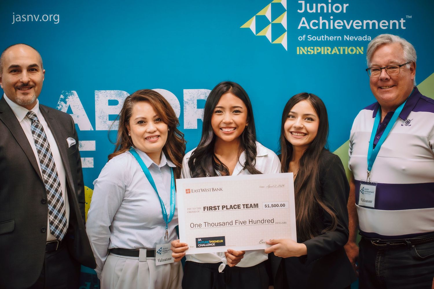 Students celebrate winning first place at Junior Achievement of Southern Nevada competition, holding a $1,500 prize check.