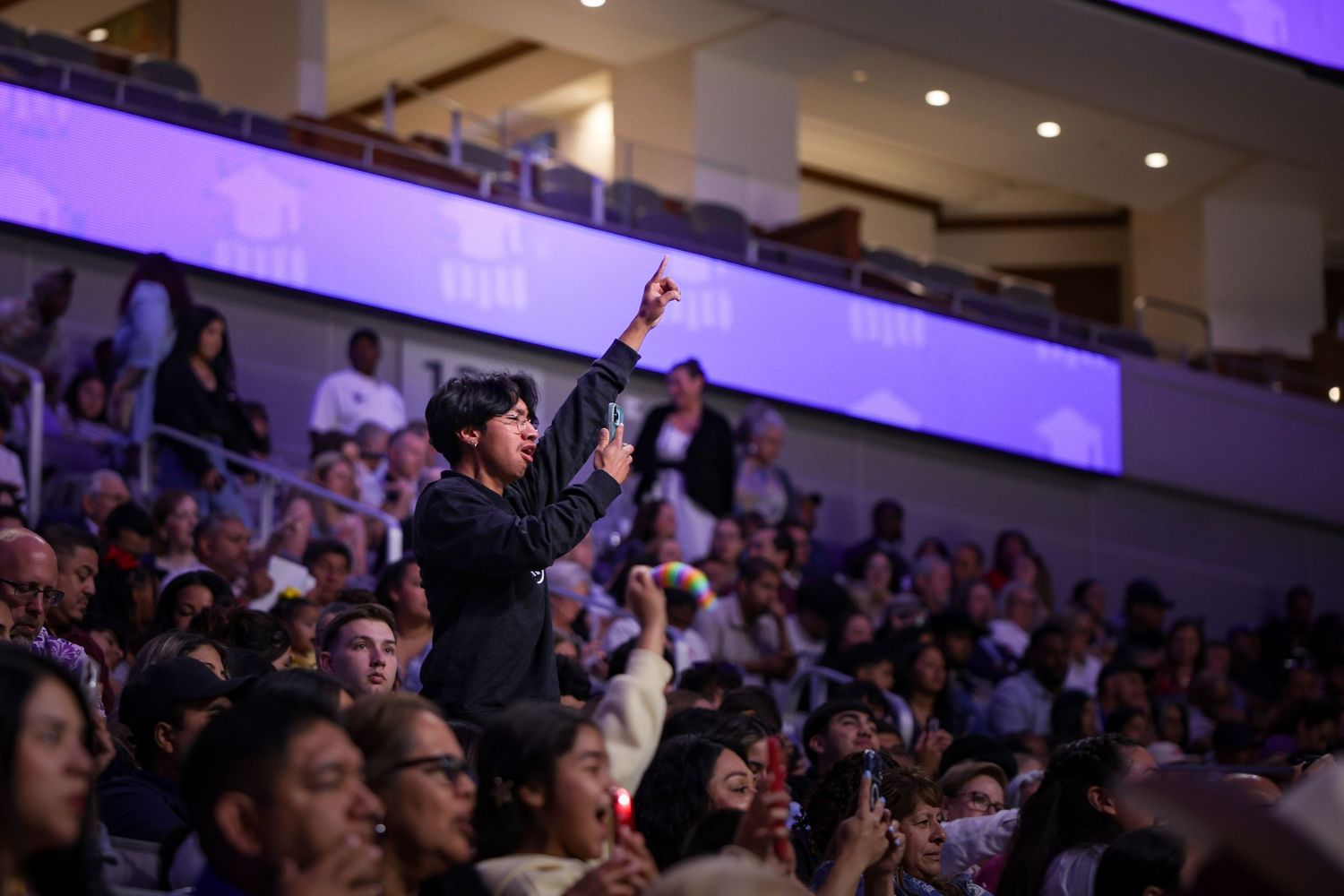 Sibling of an R.L. Paschal High School student records his child walking across the stage for graduation in Dickies Arena in Fort Worth.