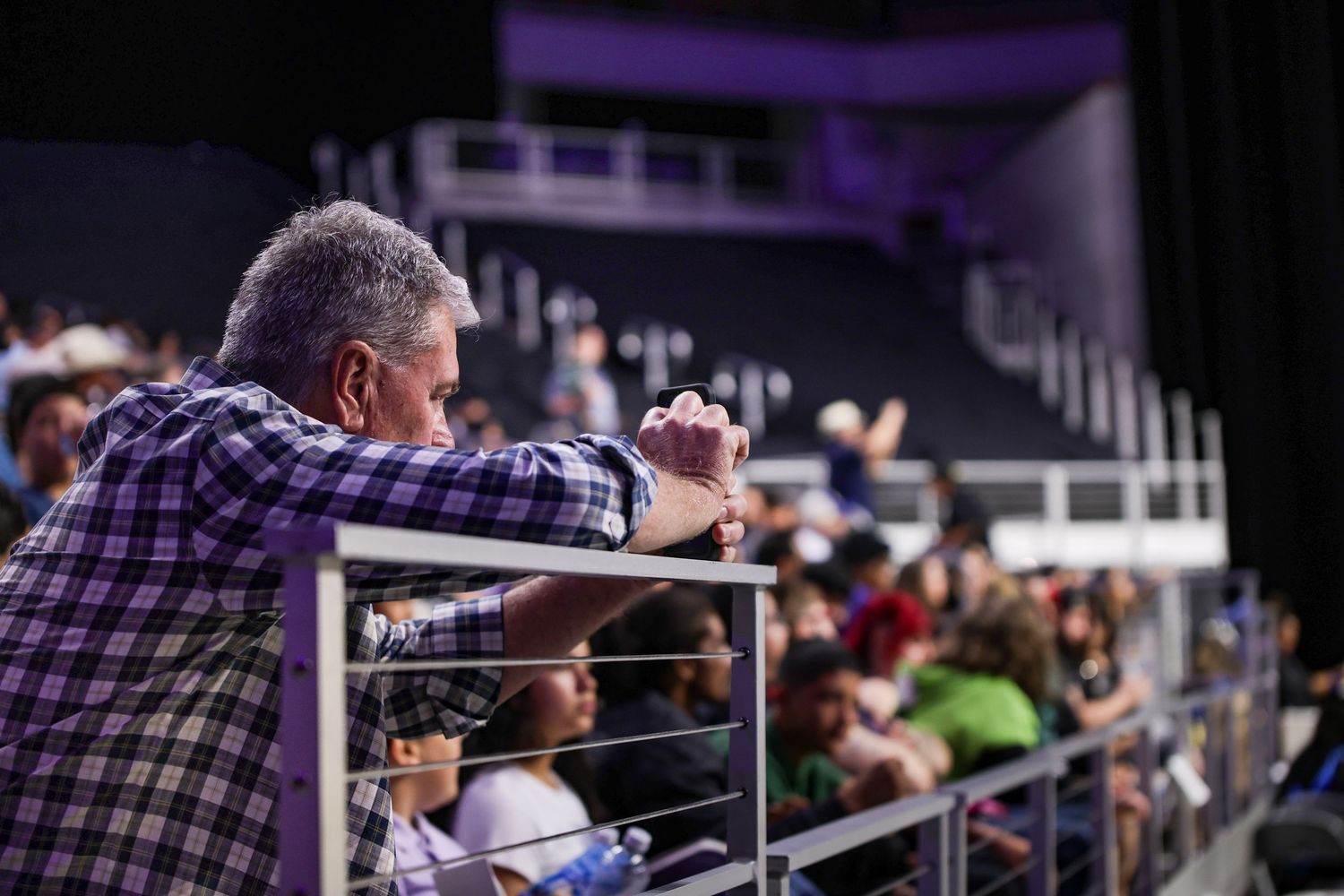 Parent of an R.L. Paschal High School student records his child walking across the stage for graduation in Dickies Arena in Fort Worth.