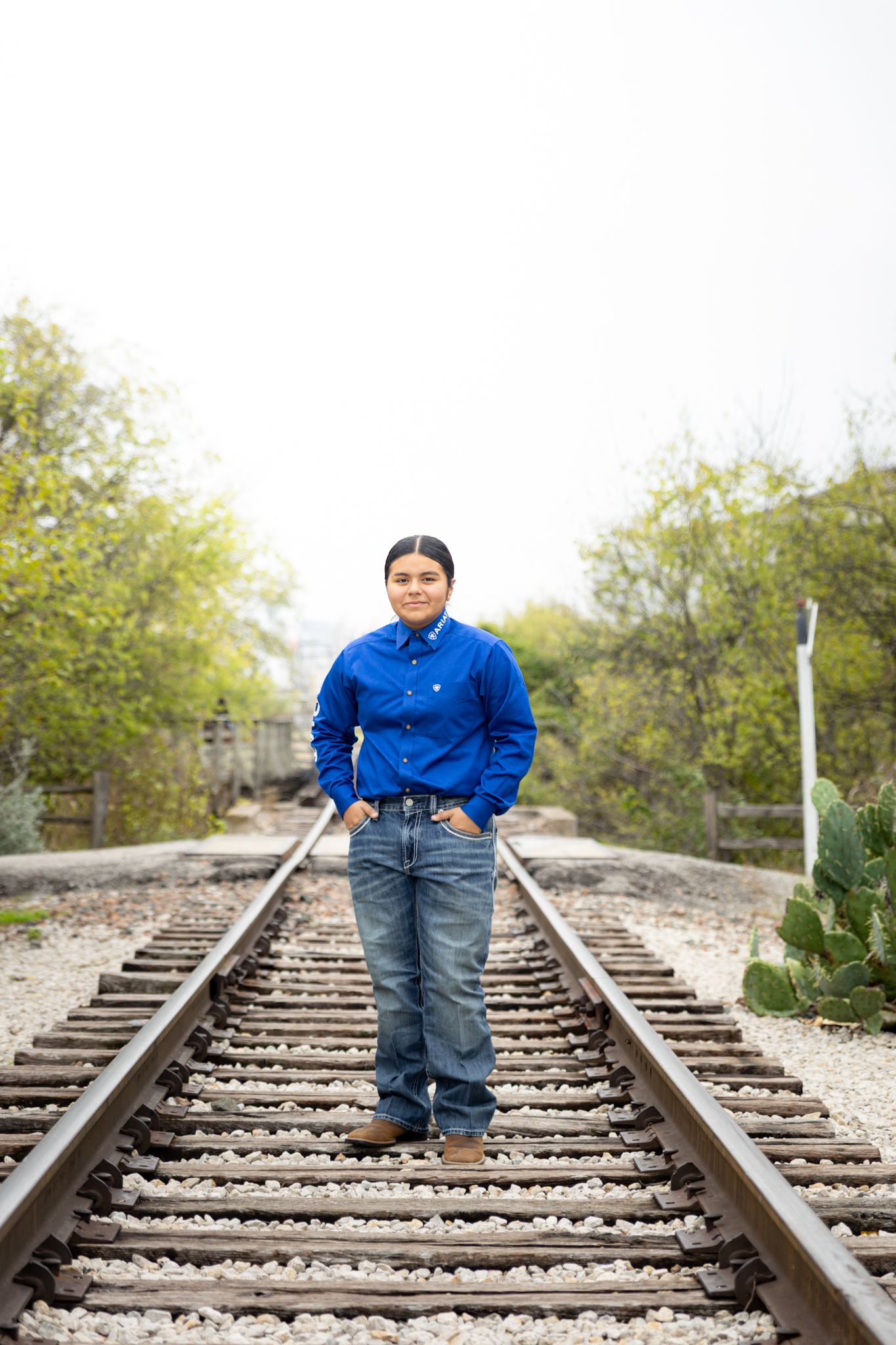 R.L. Paschal High School student poses on a train track for a Quinceañera photo in the Fort Worth, Texas Stockyards and Cactus Gardens.