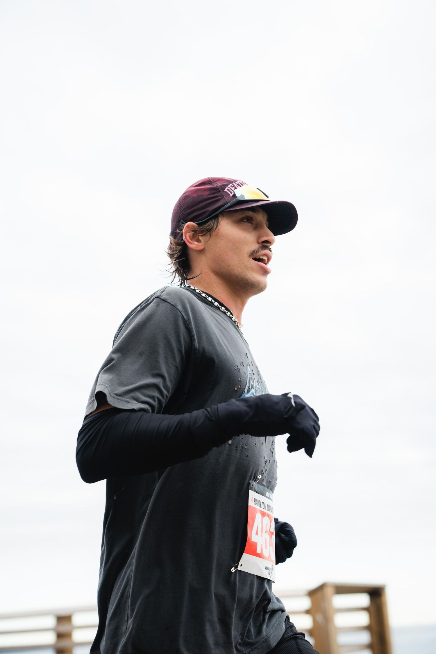 A man participates in a marathon, running energetically on a bridge with a scenic view of the city below.