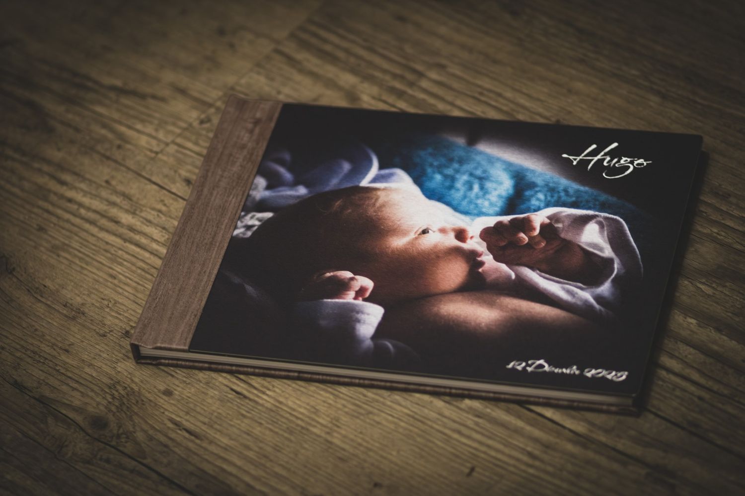 Several professional photo prints are arranged on a wooden surface showing intimate black and white portrait photography.