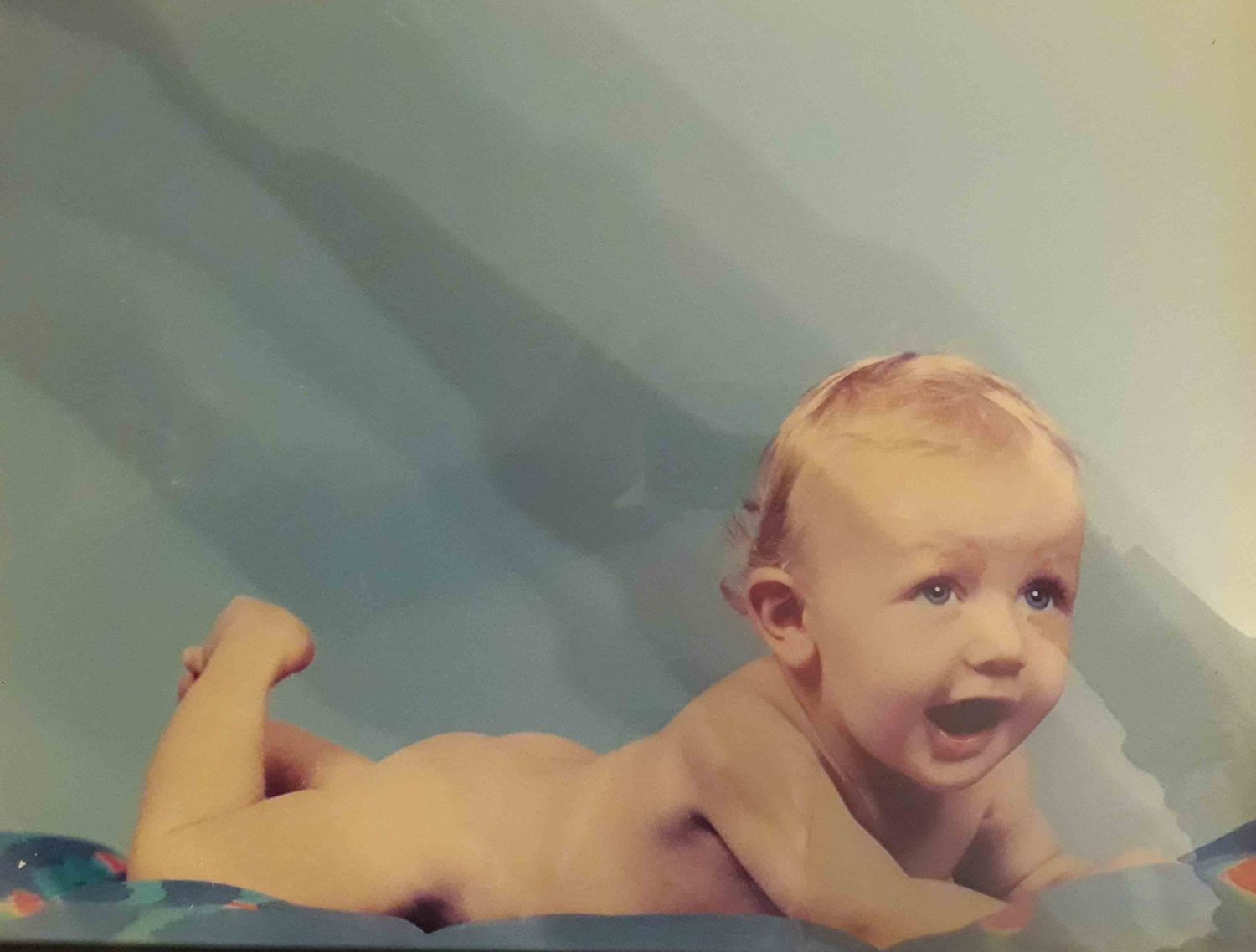 Photo d'un bébé sur une couette bleue. Photo assez ancienne