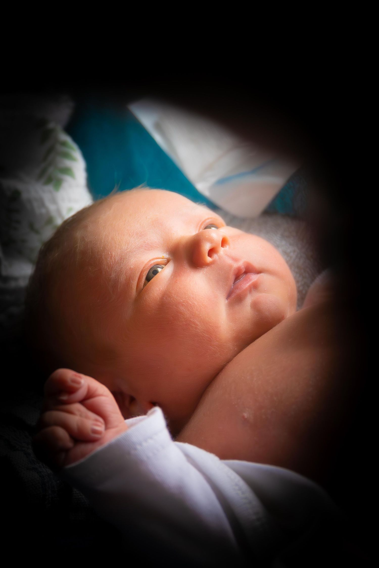 A series of soft-focus close-up shots showing a sleeping newborn baby in white blankets.