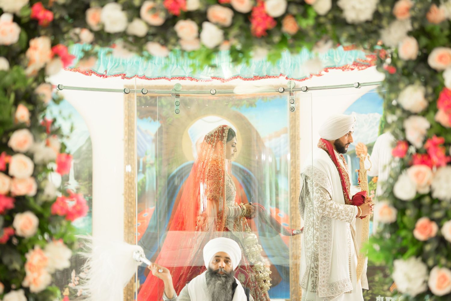 Sikh wedding ceremony couple stands beneath floral mandap adorned with pink and white roses.