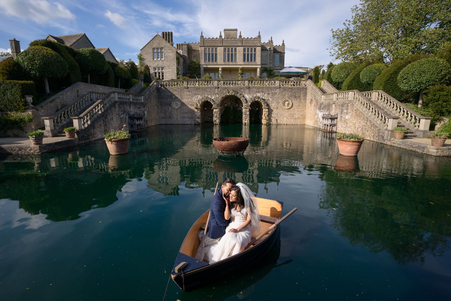 Wedding couple sharing romantic boat ride on scenic lake before a grand castle venue.