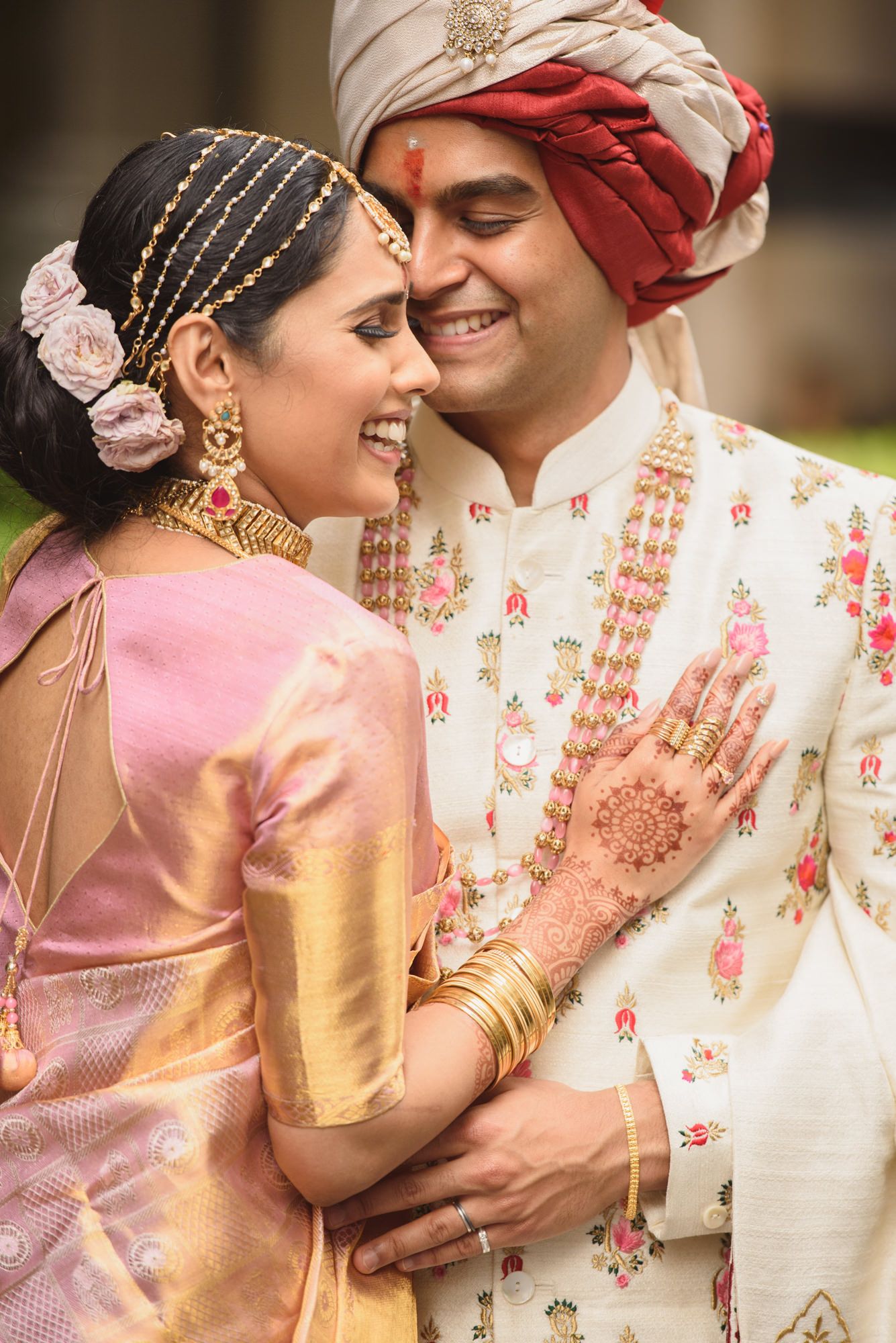 Smiling Indian bride and groom in traditional Maharashtrian wedding attire sharing joyful moment outdoors.