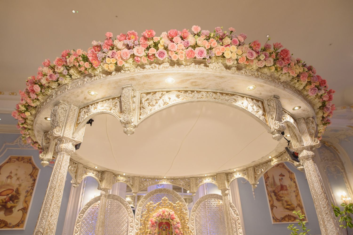 Elegant white and gold mandap ceiling adorned with pink and white roses at an Indian wedding ceremony.