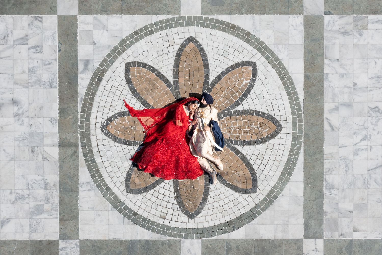 Aerial view of couple dancing on ornate mosaic floor with floral pattern design.