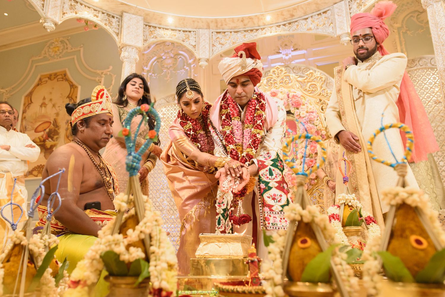 Bride and groom perform saptapadi ritual at lavishly decorated Hindu wedding mandap.