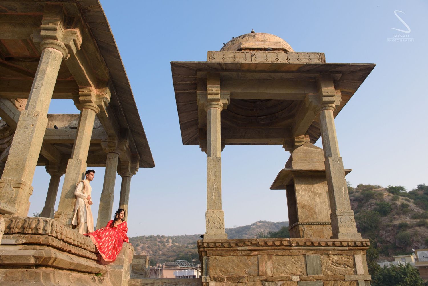 Couple posing among ancient stone pavilions at historic Rajasthani monument in Jaipur.