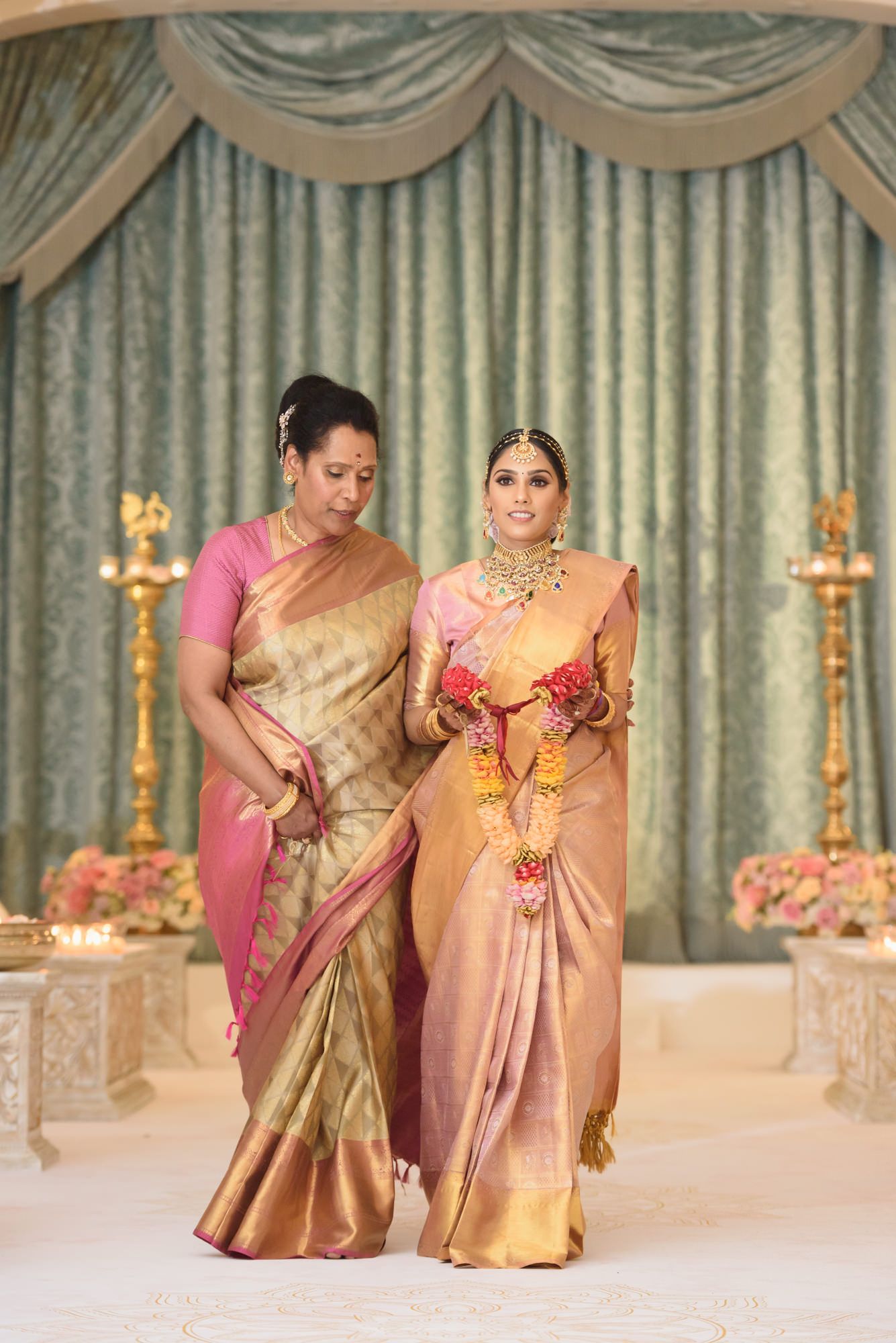 Mother escorts bride in pink and gold Kanjivaram saree at Hindu wedding ceremony.