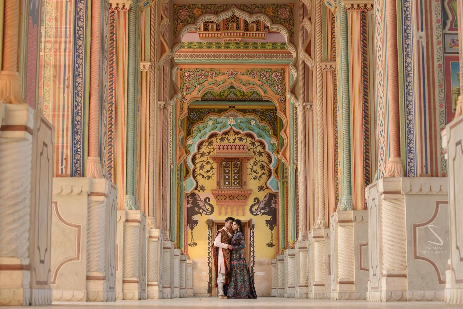 Couple embracing in stunning colorful ornate Patrika Gate corridor in Jaipur, Rajasthan.