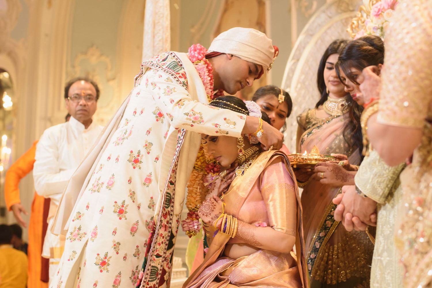 Groom applies sindoor to bride during traditional Hindu wedding ceremony ritual.