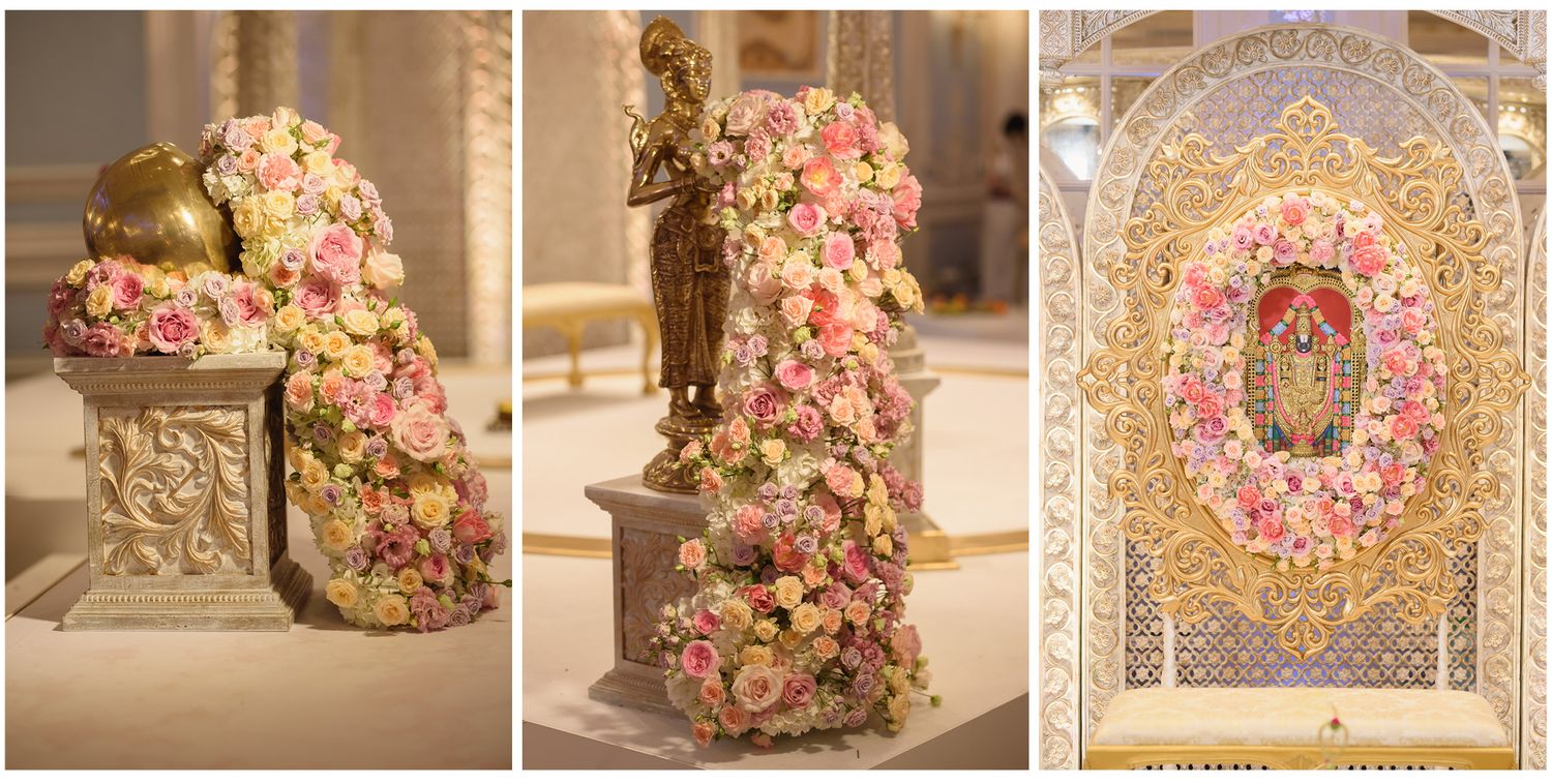 Elegant floral arrangements with pink roses adorning golden statues and ornate decor at a luxurious wedding venue.