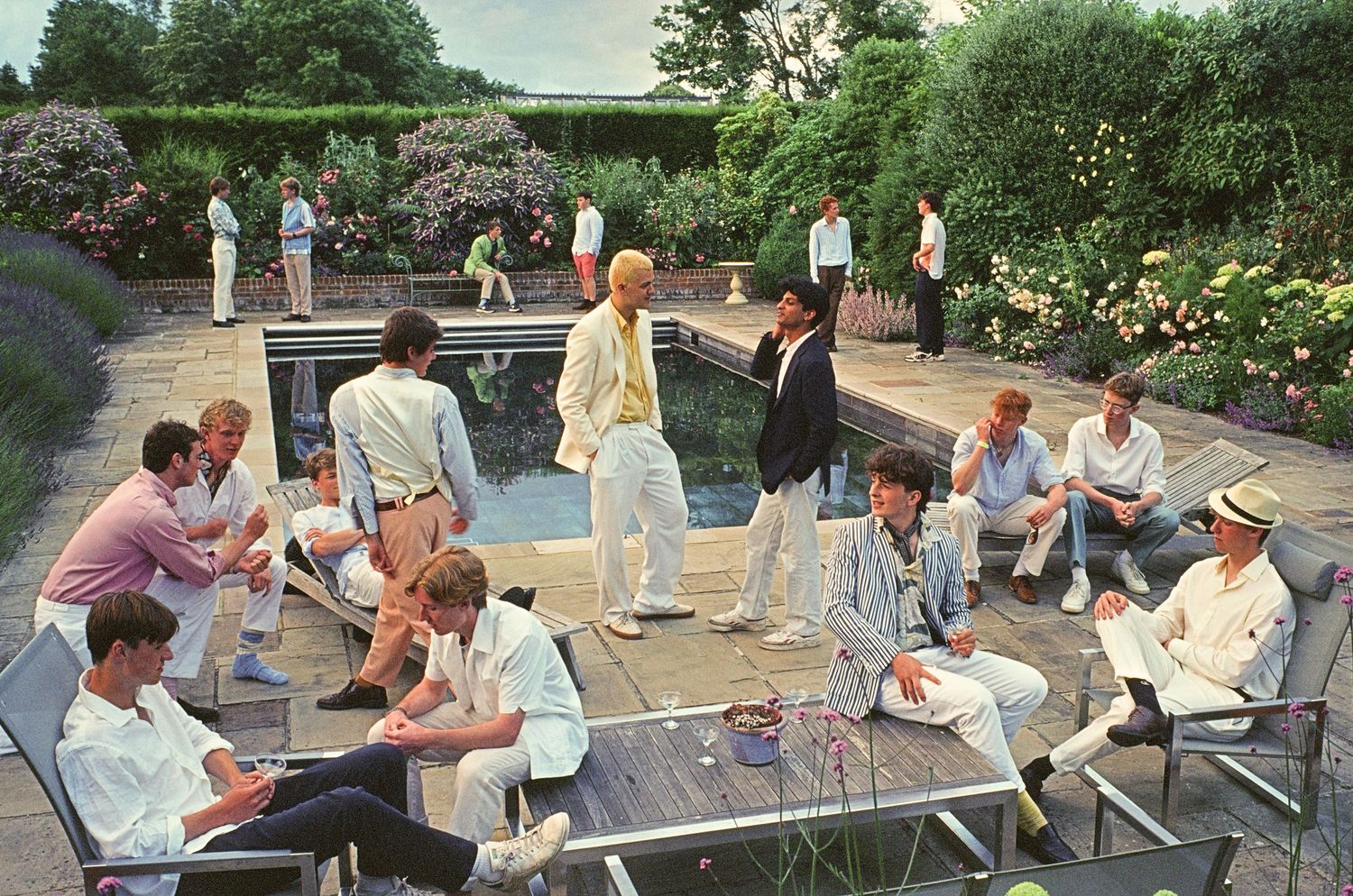 Vintage photo of people gathered around outdoor ping pong tables on a sunny garden patio.