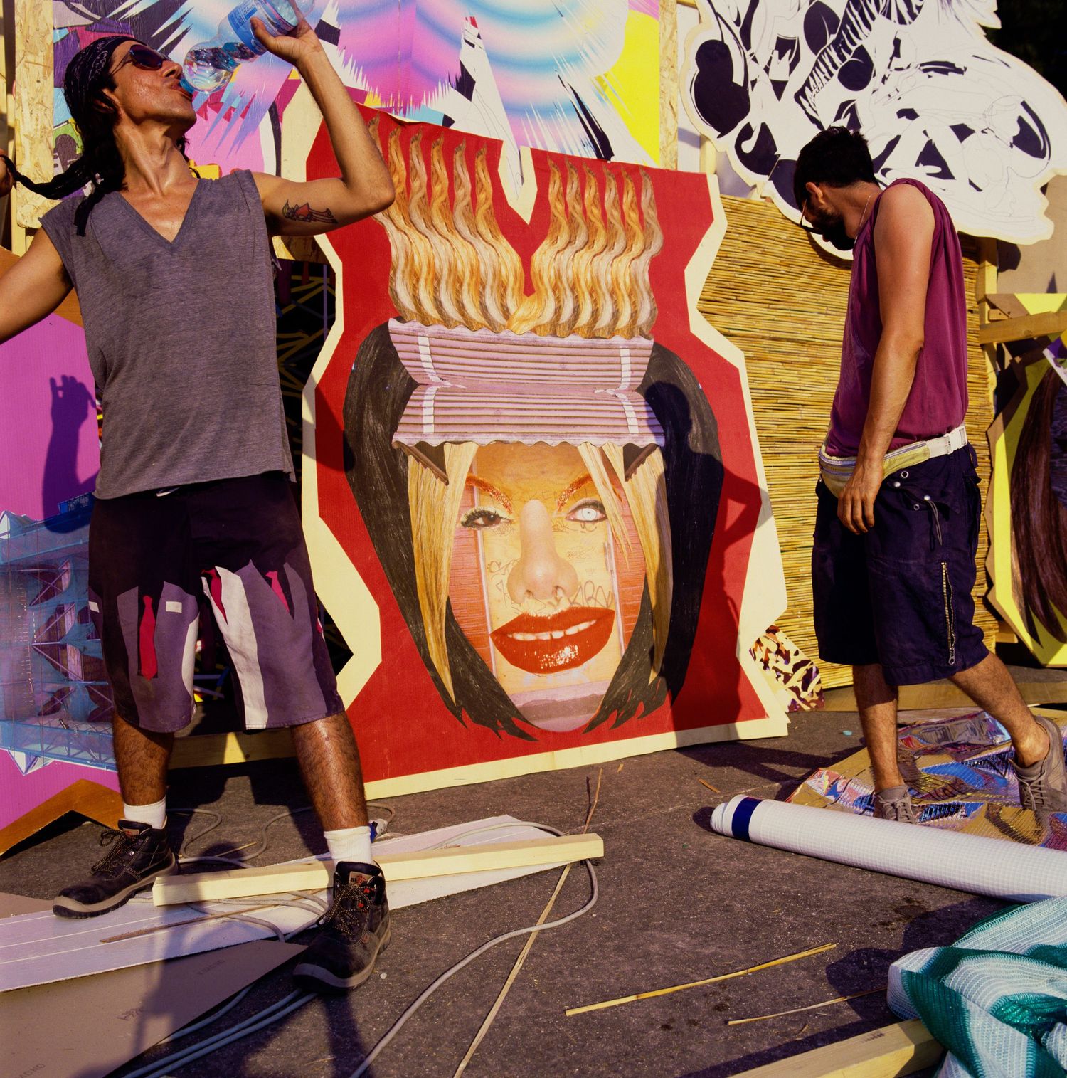 Colorful pop art style portraits displayed on studio floor with people walking.