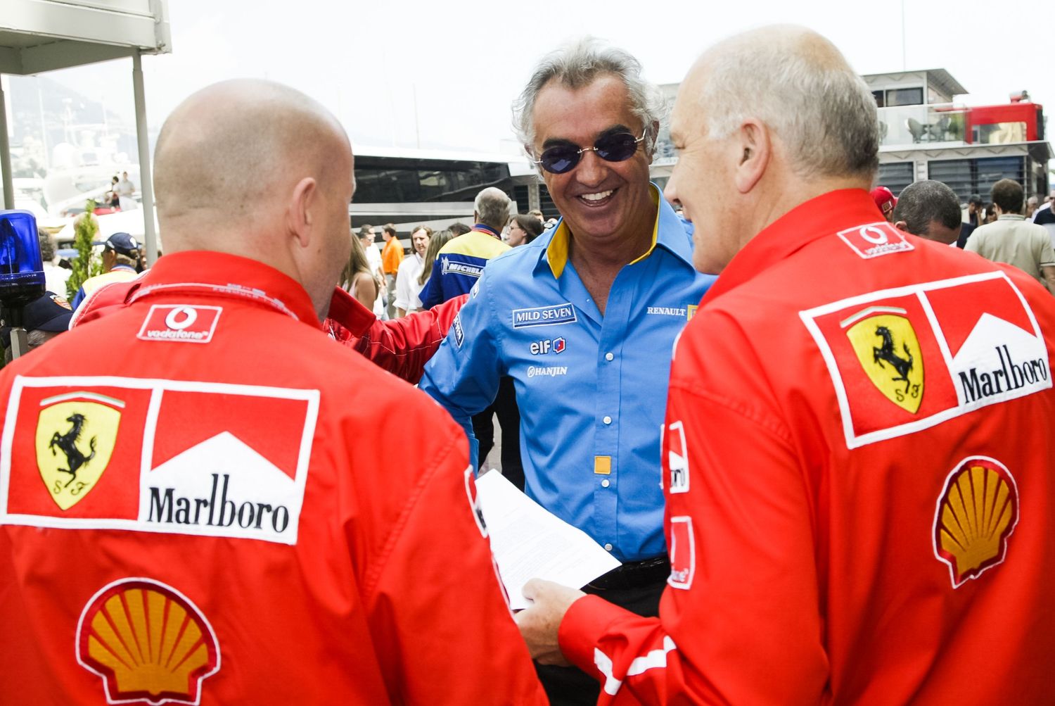Ferrari Formula 1 team members in red uniforms gather at racing event.