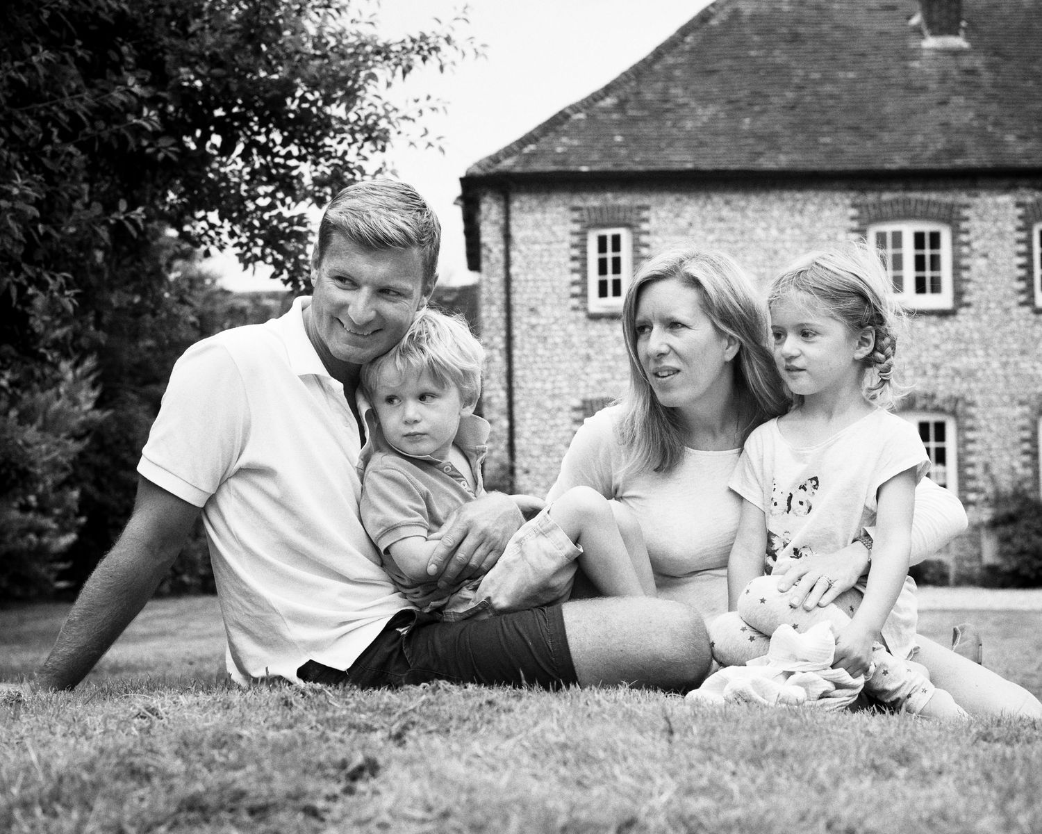 A series of candid black and white family portraits showing relaxed moments on a lawn in front of country cottage.