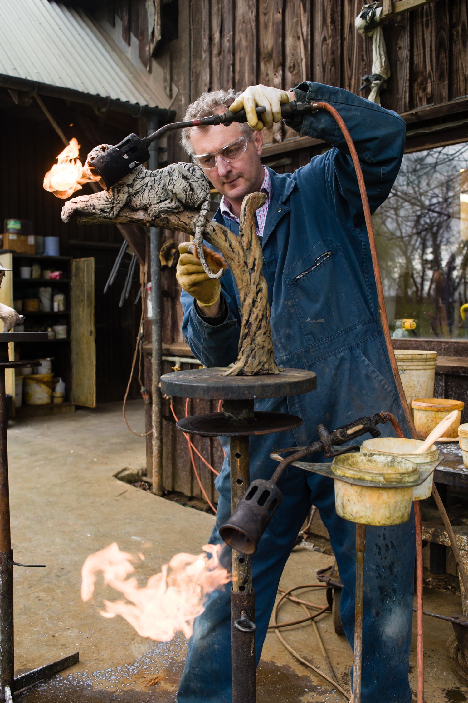Metalworker using torch and tools in workshop with dramatic flames.
