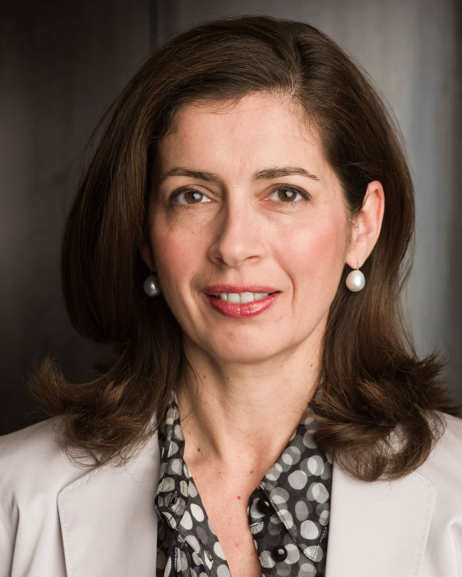 Portrait series of woman in polka dot blouse and white blazer with styled dark hair.