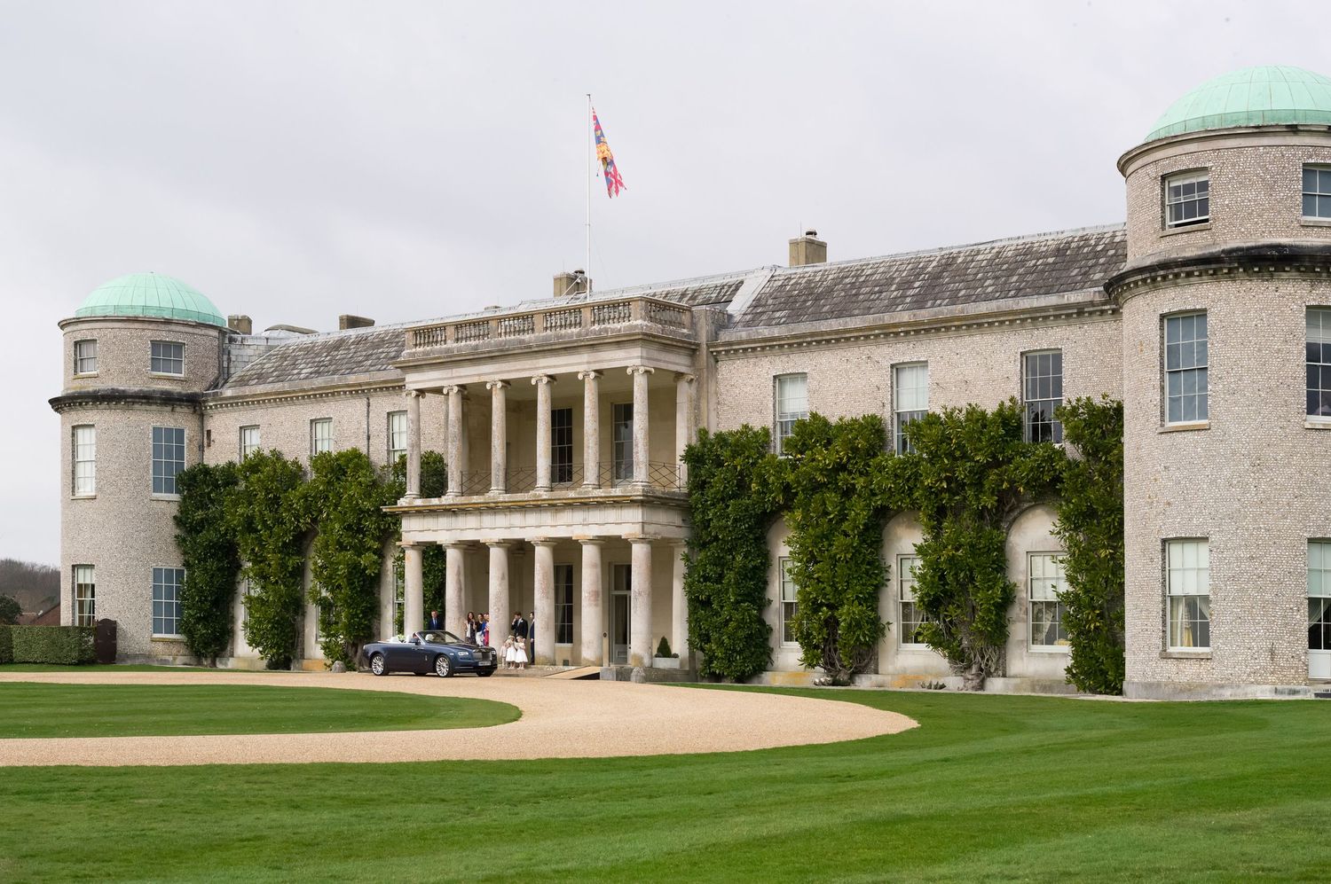 Panoramic view of a grand historic building with classical architecture and manicured lawns.