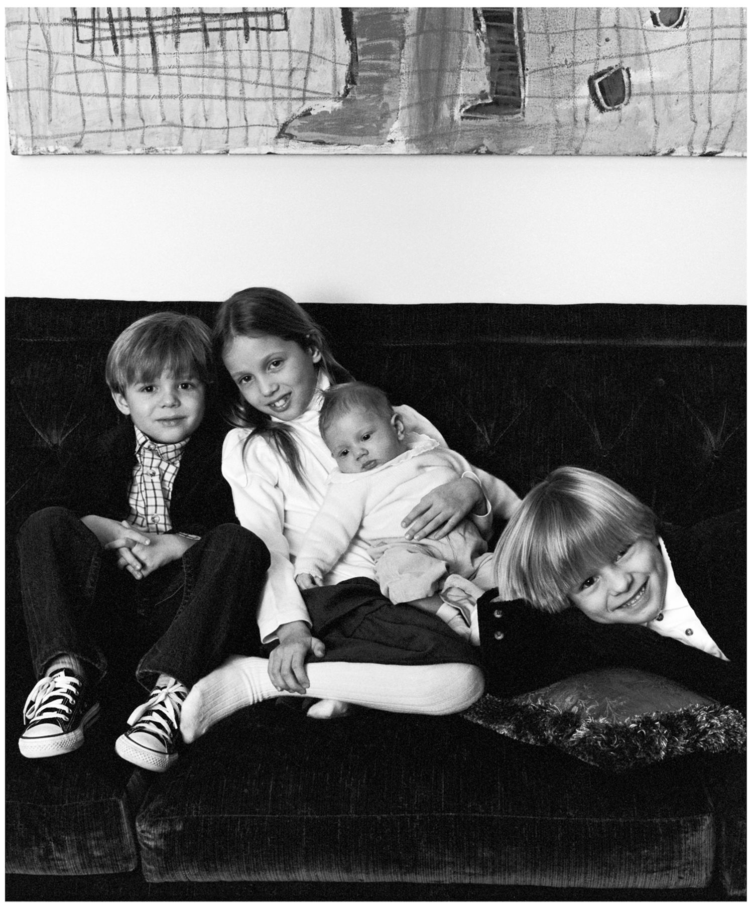 Black and white photograph of family relaxing together on vintage couch.