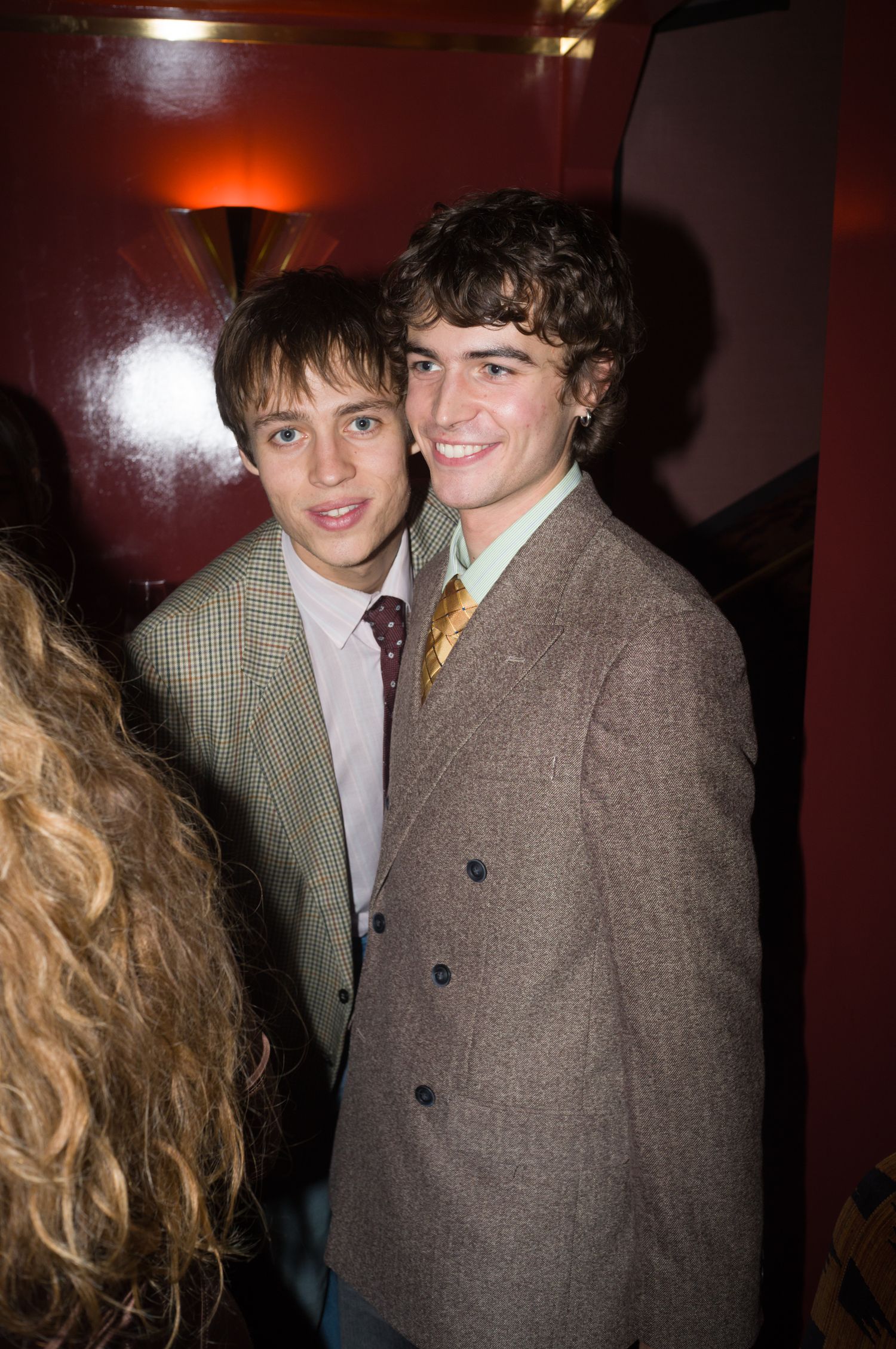 Two people in tweed jackets pose together at a social event.