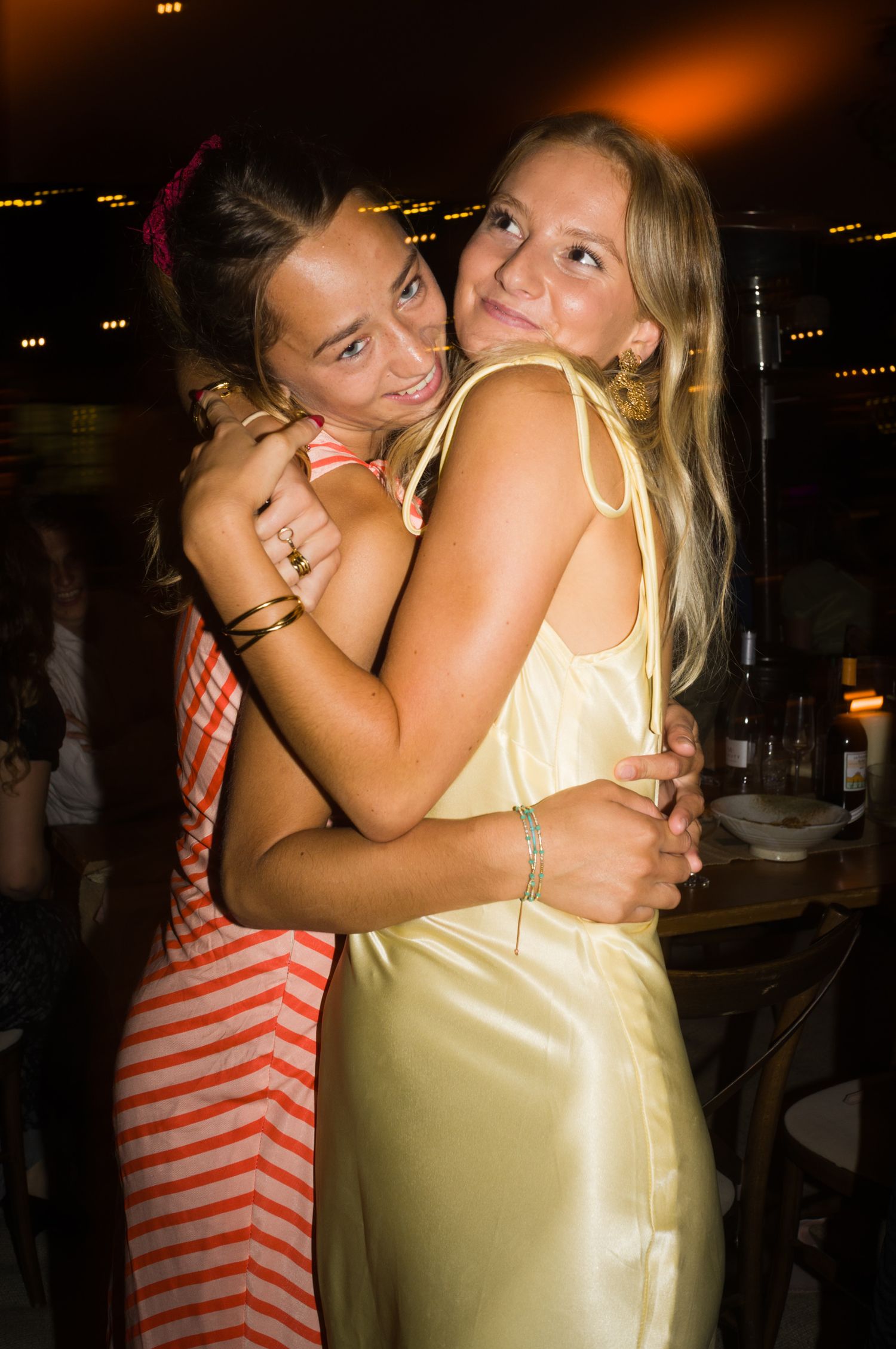 Two friends sharing a joyful embrace at a nighttime celebration.