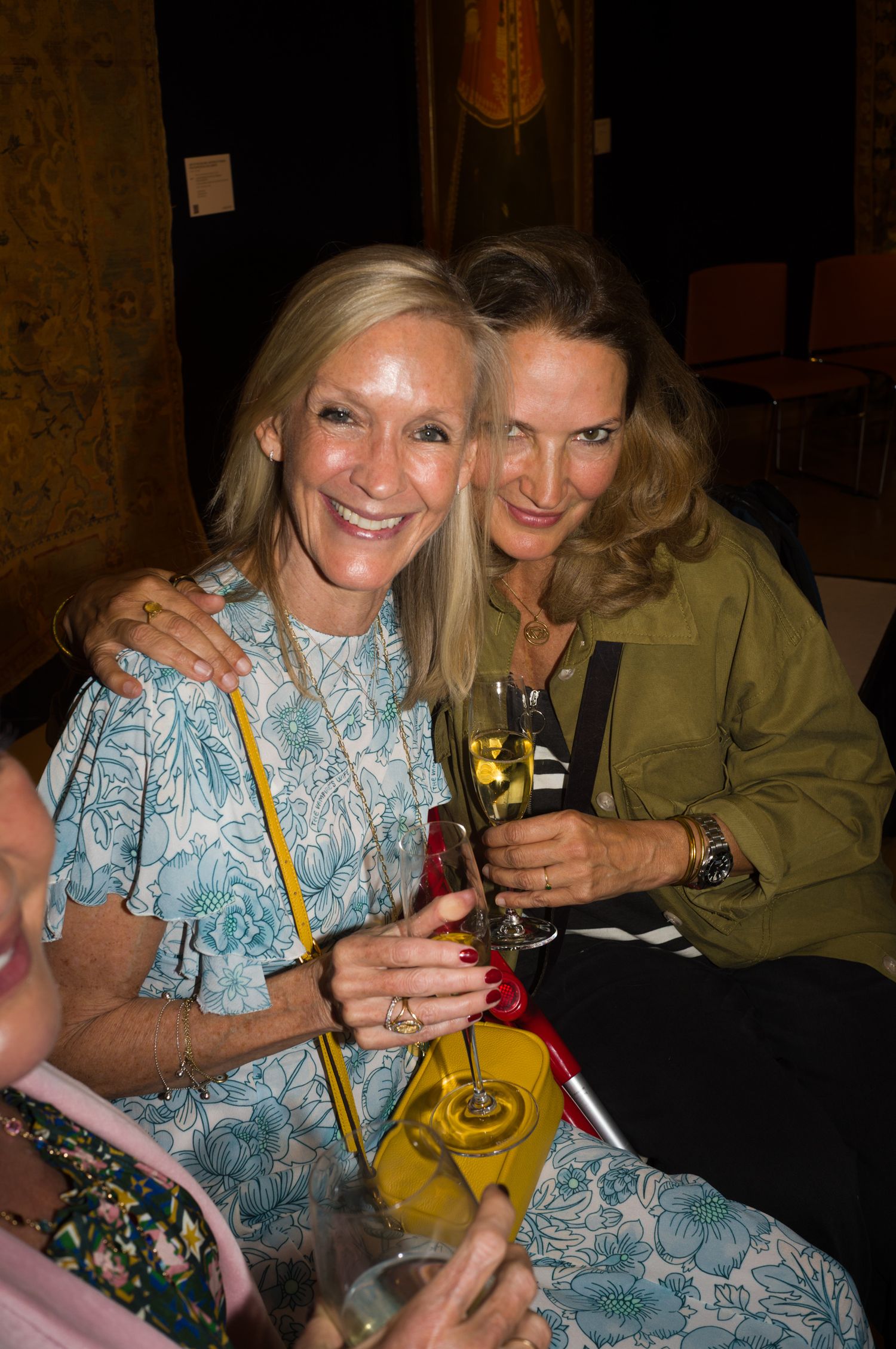 Two friends enjoying drinks and smiling at a social gathering.