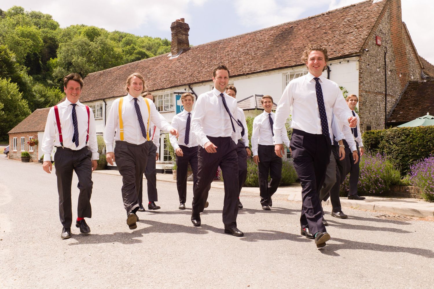 Groomsmen walk in formation along stone path during wedding celebration.