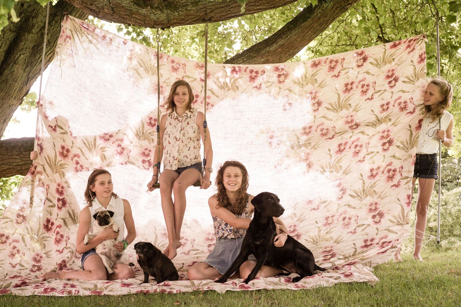 Family photo session in a garden with floral backdrop and natural lighting.