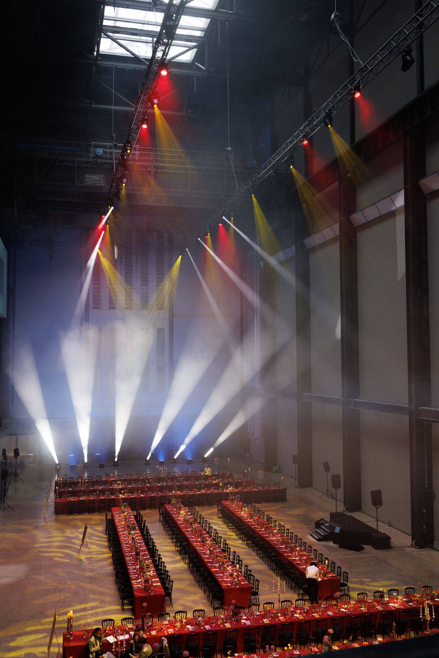 Large event space with dramatic lighting and rows of red chairs set up for a formal gathering.