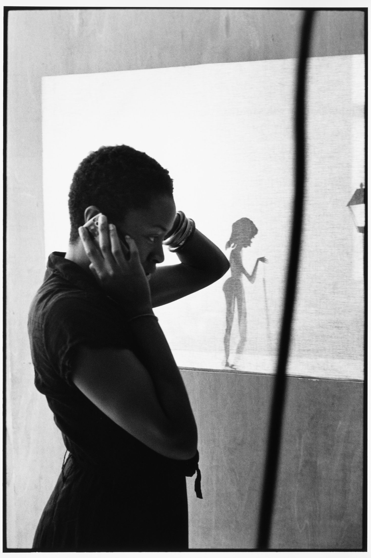 Silhouetted artist Cara Walker against backlit wall in dramatic black and white composition.