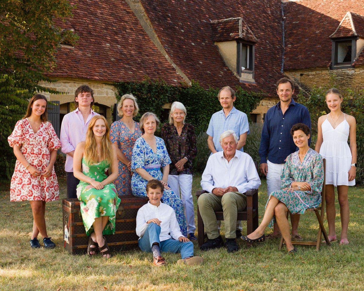 Extended family portrait taken outdoors in front of traditional countryside manor in France.