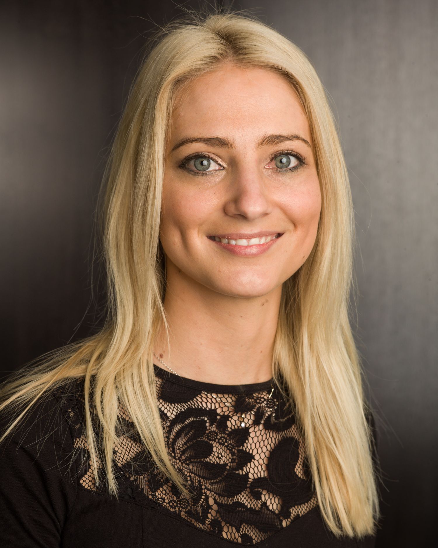 Business headshot Studio portrait series featuring someone in black lace top against dark background.