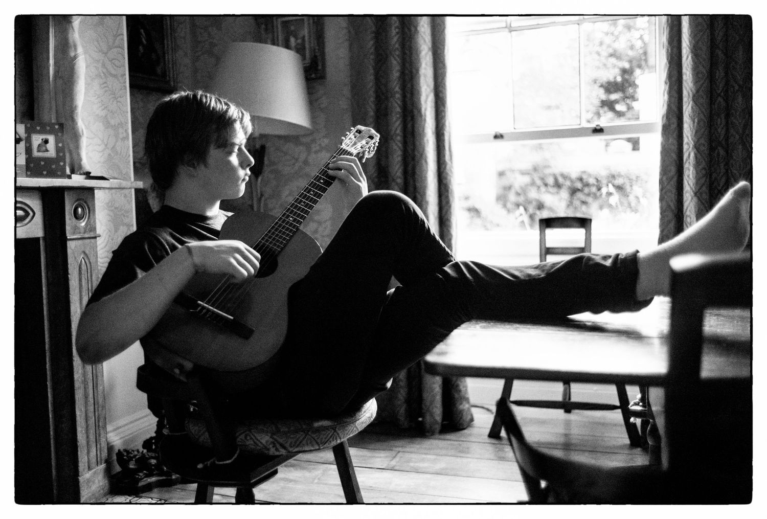 Series of silhouetted figure, guitarist Ollie Clark by a window in black and white photography. Leica M