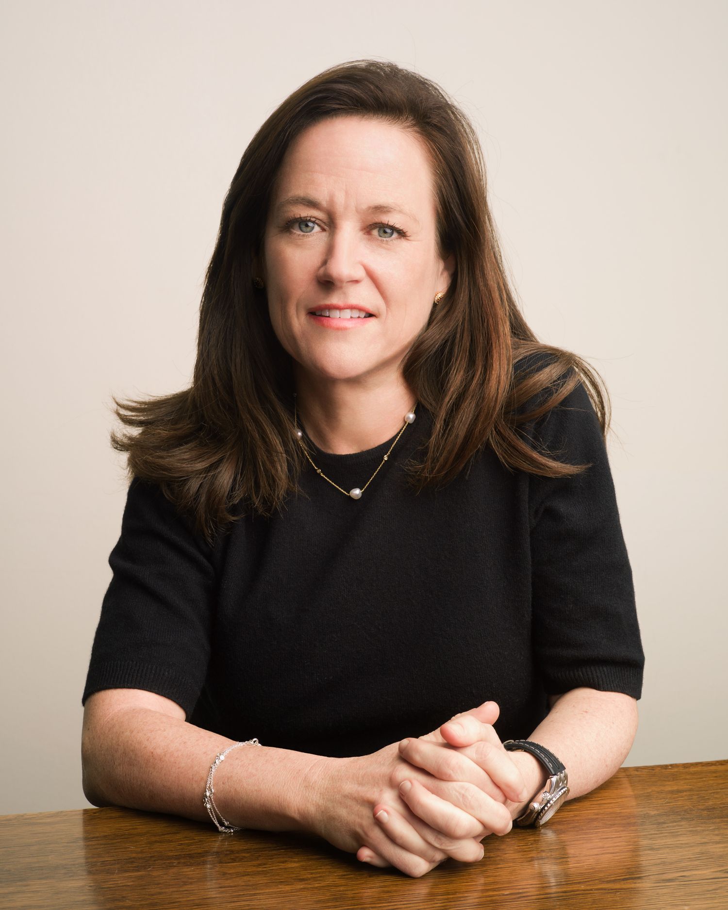 Professional series of brunette woman in black attire resting on wooden table with different poses.