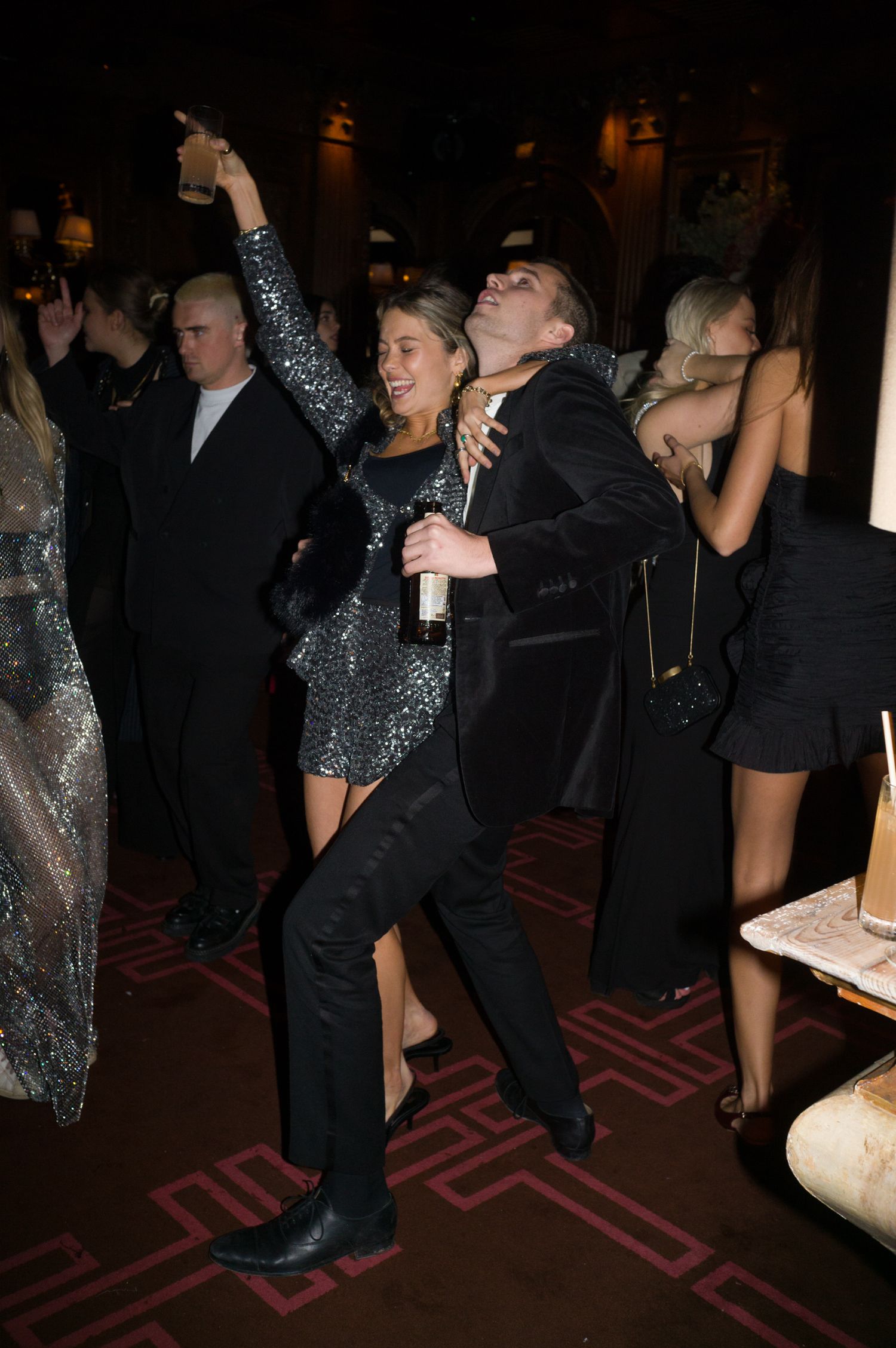 People dancing and celebrating at a dark nightclub with sparkly dresses and formal attire.